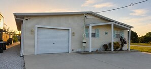 Ein eingeschossiges Gebäude mit Garage, überdachter Veranda und kleinem Vorgarten.