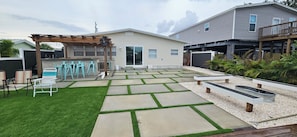 Ein Garten mit Terrasse, Sitzgelegenheit im Freien und einer Pergola.