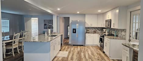 A modern kitchen with white cabinetry, a central island, and a stainless steel refrigerator.