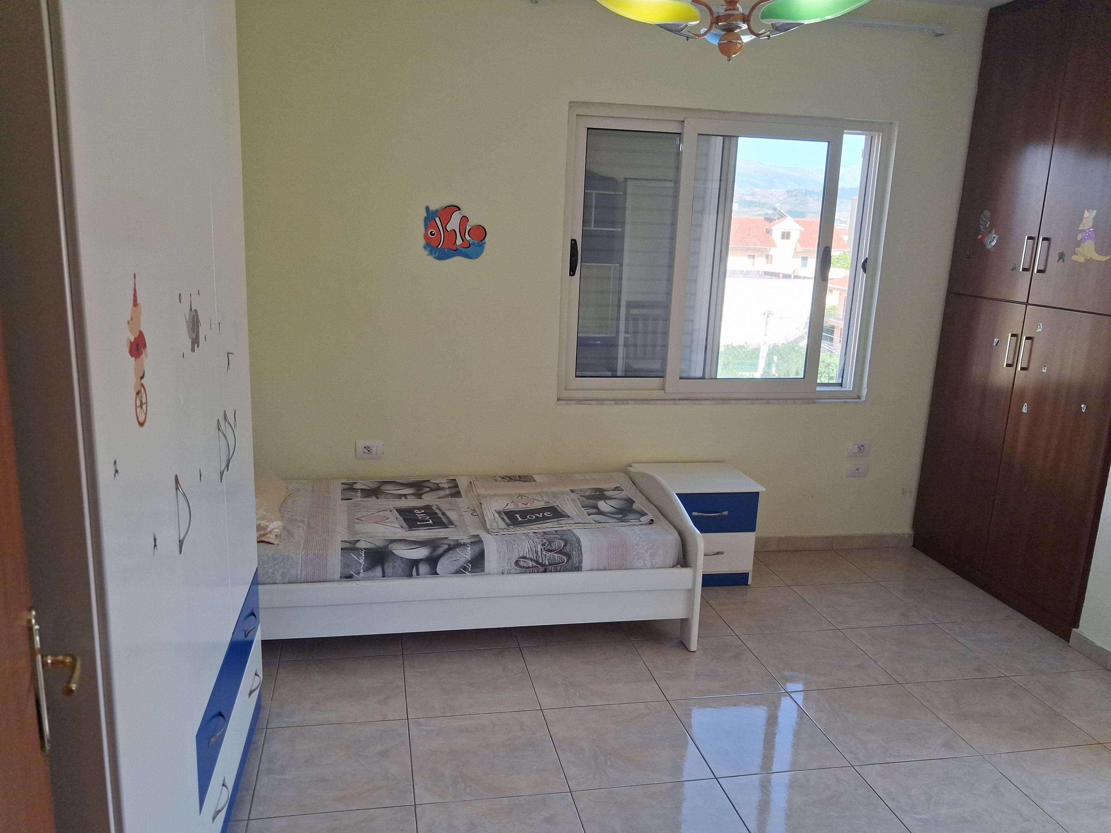 Ein Schlafzimmer mit Bett, Kleiderschrank, Fenster und Deckenventilator.