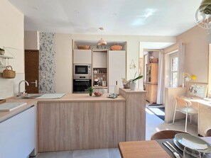 A modern kitchen with a central island, built-in appliances, and a dining area with a table and chairs.