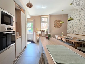 Una cocina moderna con electrodomésticos integrados, un comedor con mesa y sillas, y vistas al exterior.