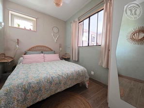 Un dormitorio con cama, una ventana, un atrapasueños y un adorno en la pared.