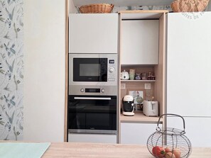 A kitchen with a built-in oven, microwave, and a coffee maker on the counter.