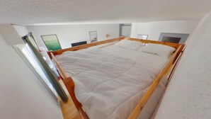 A room with a bed, wooden headboard, white walls, and a door. - Central apartment with wifi - 4 guests (Les Rousses)