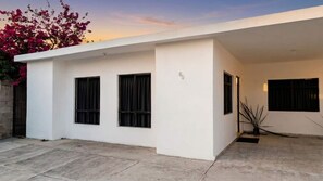 A modern building with a flat roof, three windows with black frames, and a concrete floor.