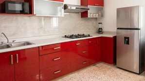 A kitchen with red cabinets, a stainless steel refrigerator, a microwave, and a gas stove.