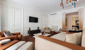 Una sala de estar moderna con un televisor de pantalla plana montado en la pared, sofás de cuero, una mesa de centro y una consola decorativa.