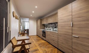 A modern kitchen with wooden cabinets, a marble backsplash, and a dining area with wooden chairs. - IN ONE OF PARIS'S MOST PRESTIGIOUS & CHARMING NEIGHBORHOODS-  SAINT-GERMAIN (Paris)