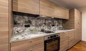 Une cuisine moderne avec des meubles en bois, un pare-feu en marbre et des appareils électroménagers en acier inoxydable.
