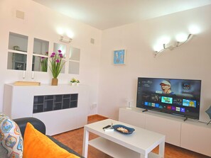 Ein modernes Wohnzimmer mit Flachbildfernseher, weißen Möbeln und Dekorationselementen.
