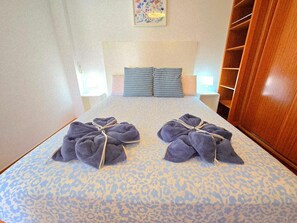Ein Hotelzimmer mit einem Bett, zwei Kissen, einem Nachttisch und einem Holzschrank.