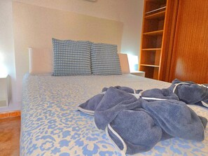 Ein Schlafzimmer mit einem Bett, Kissen, einem Holzschrank und einem Badezimmerbereich.