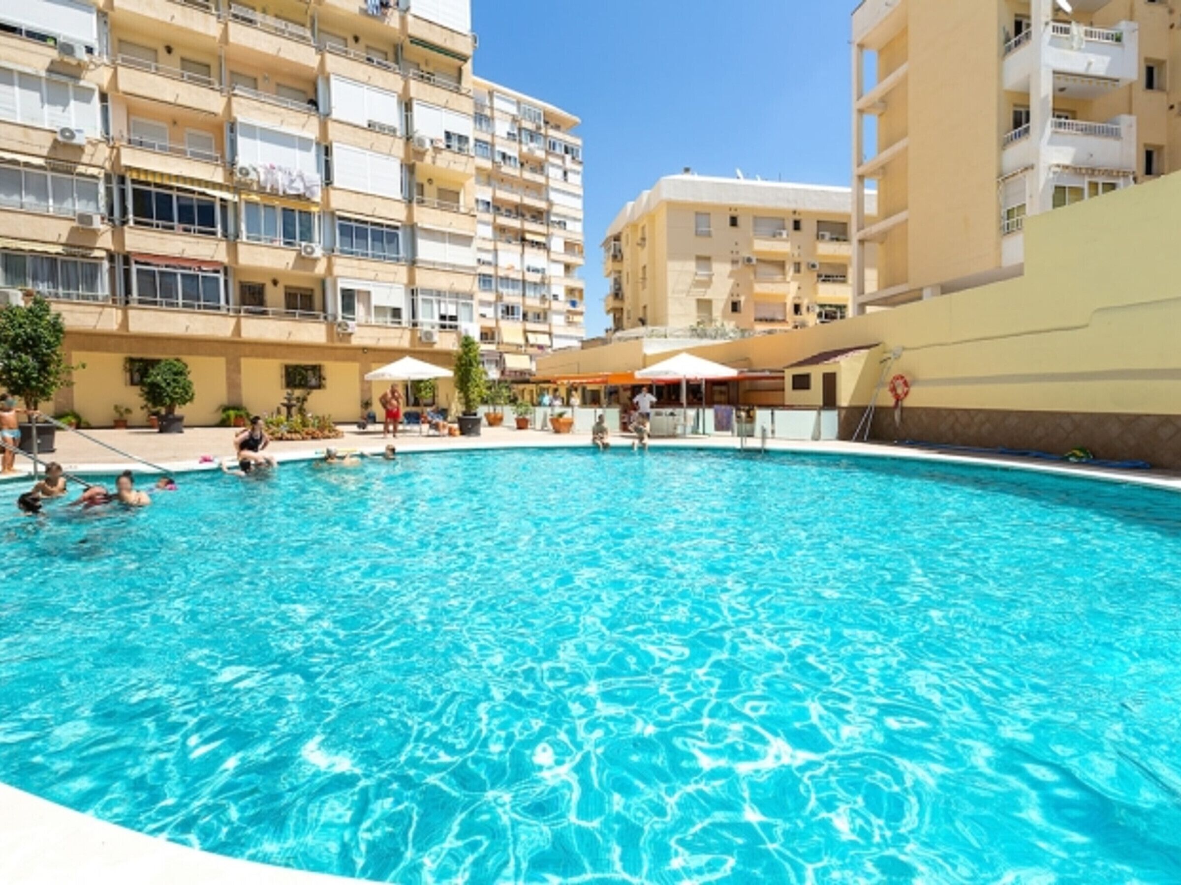 Una piscina rodeada por un edificio de varios pisos con balcones.