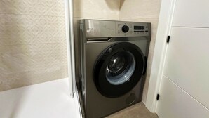 A compact, modern laundry room with a front-loading washing machine, a control panel, and a small cabinet above the machine. - Central seaview studio with pool in Torremolinos (Torremolinos)
