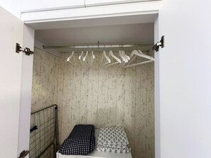 Ein kleines Zimmer mit einem Bett, einem Heizkörper und einem Wäscheständer.