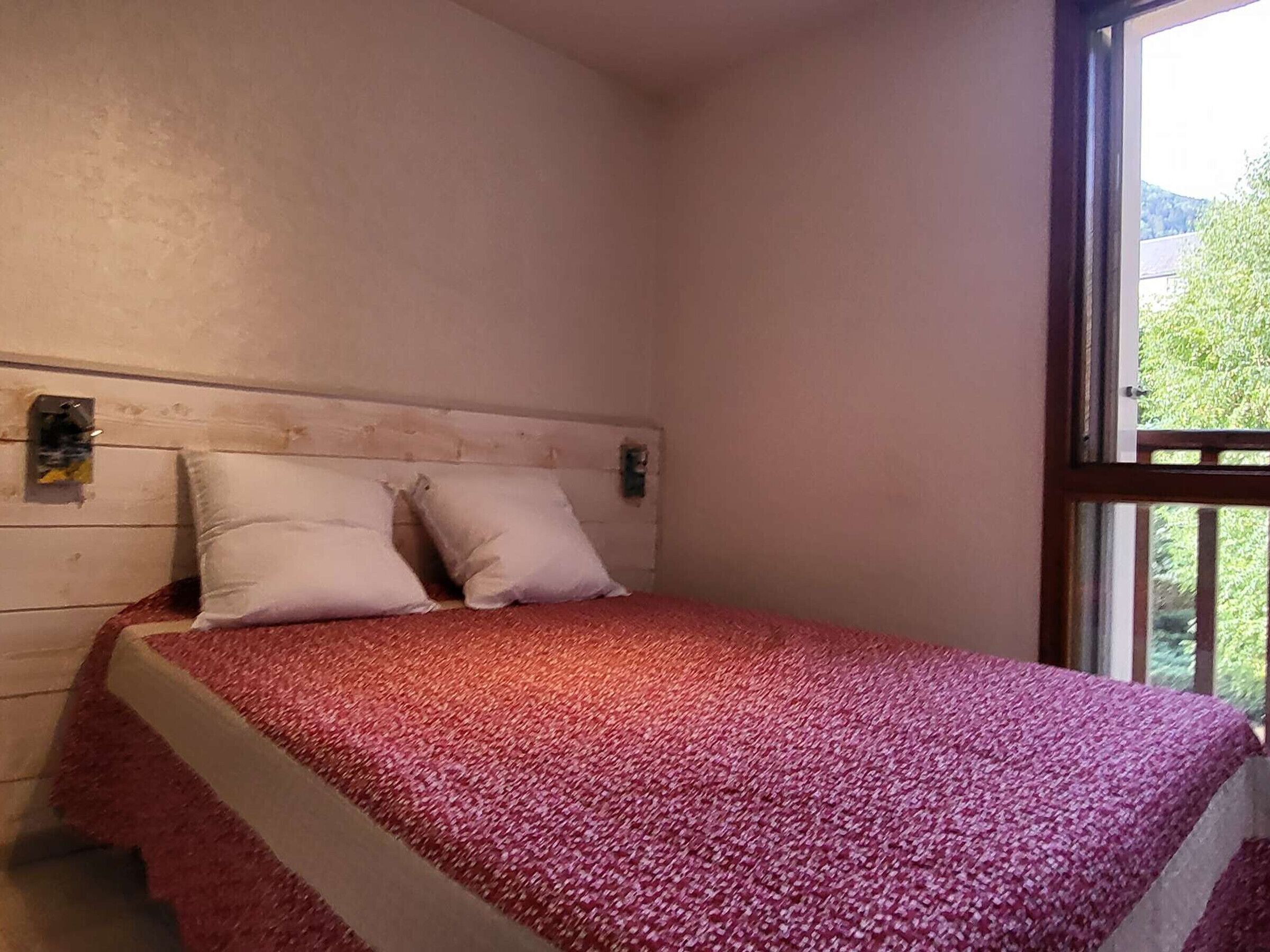 Une chambre à coucher avec un lit, des oreillers, une tête de lit et une fenêtre.