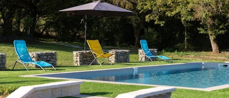 A swimming pool with a stone wall and a wooden deck.