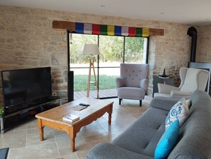 Ein Wohnzimmer mit Steinwand, Fernseher, Sofa, Couchtisch und Sessel.