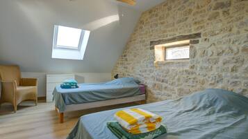 Ein Schlafzimmer mit zwei Betten, einem Deckenventilator und einer Steinwand.