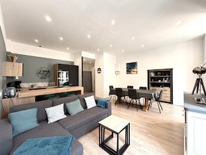 A modern living space with a sofa, dining table, and kitchen area. - Apartment in city center with WIFI - 6 guests (La Bourboule)