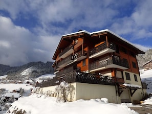 Un chalet à plusieurs étages, doté de balcons, situé dans une région montagneuse enneigée.