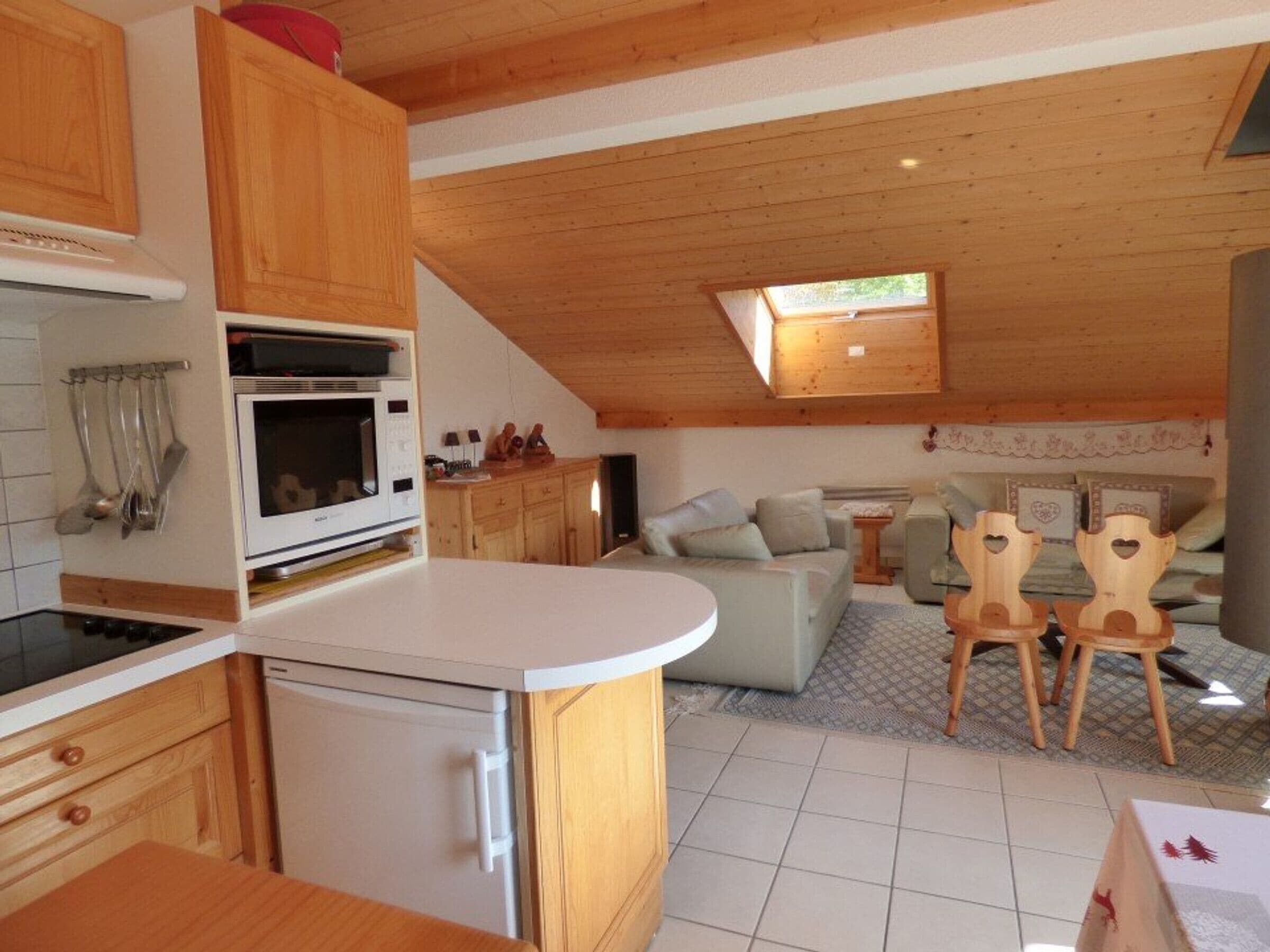 A compact kitchen with a microwave, stove, and wooden cabinets.