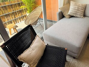 A modern living room with a grey sofa, a black woven chair with a cushion, and a wicker chair. - 3BR Tulum Penthouse with Private Pool & Jungle Views (Tulum)