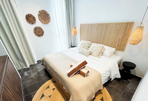 A bedroom with a bed, bedside tables, a wall-mounted light fixture, and a decorative wall piece. - 3BR Tulum Penthouse with Private Pool & Jungle Views (Tulum)