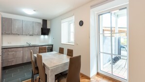 Una cocina moderna con gabinetes grises, una estufa integrada y un comedor con una mesa y sillas de mármol.
