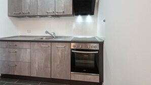 Una cocina con gabinetes grises, un lavamanos de acero inoxidable y un horno empotrado.