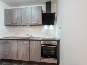 Una cocina con gabinetes grises, un lavamanos de acero inoxidable y un horno empotrado.