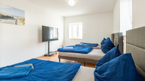 Una habitación de hotel con dos camas, televisión y ventana.