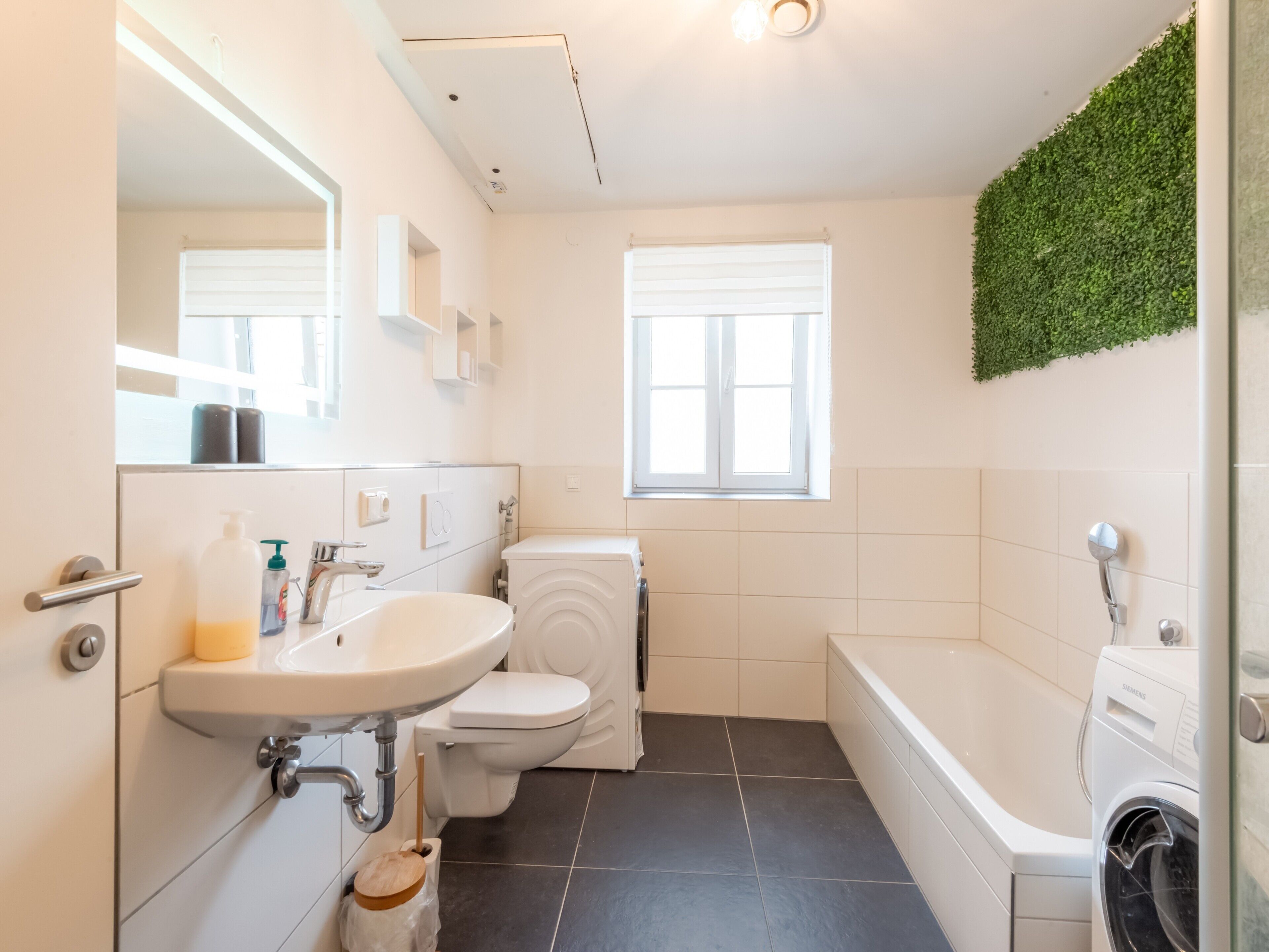 A modern bathroom with a white sink, toilet, and bathtub.