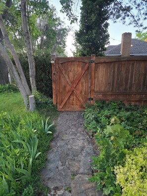 A wooden gate with a stone pathway leading to a house.