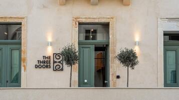 Facciata di un edificio con un'insegna che recita 'THE THREE DOORS' e due applique illuminate.