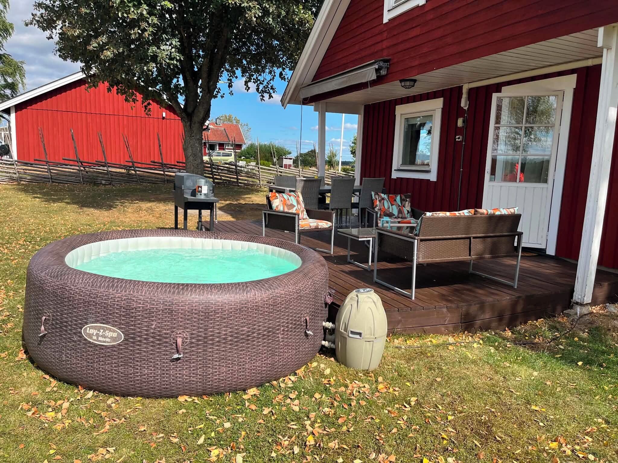 An outdoor swimming pool with a wicker design, a barbecue grill, and a deck with outdoor furniture.