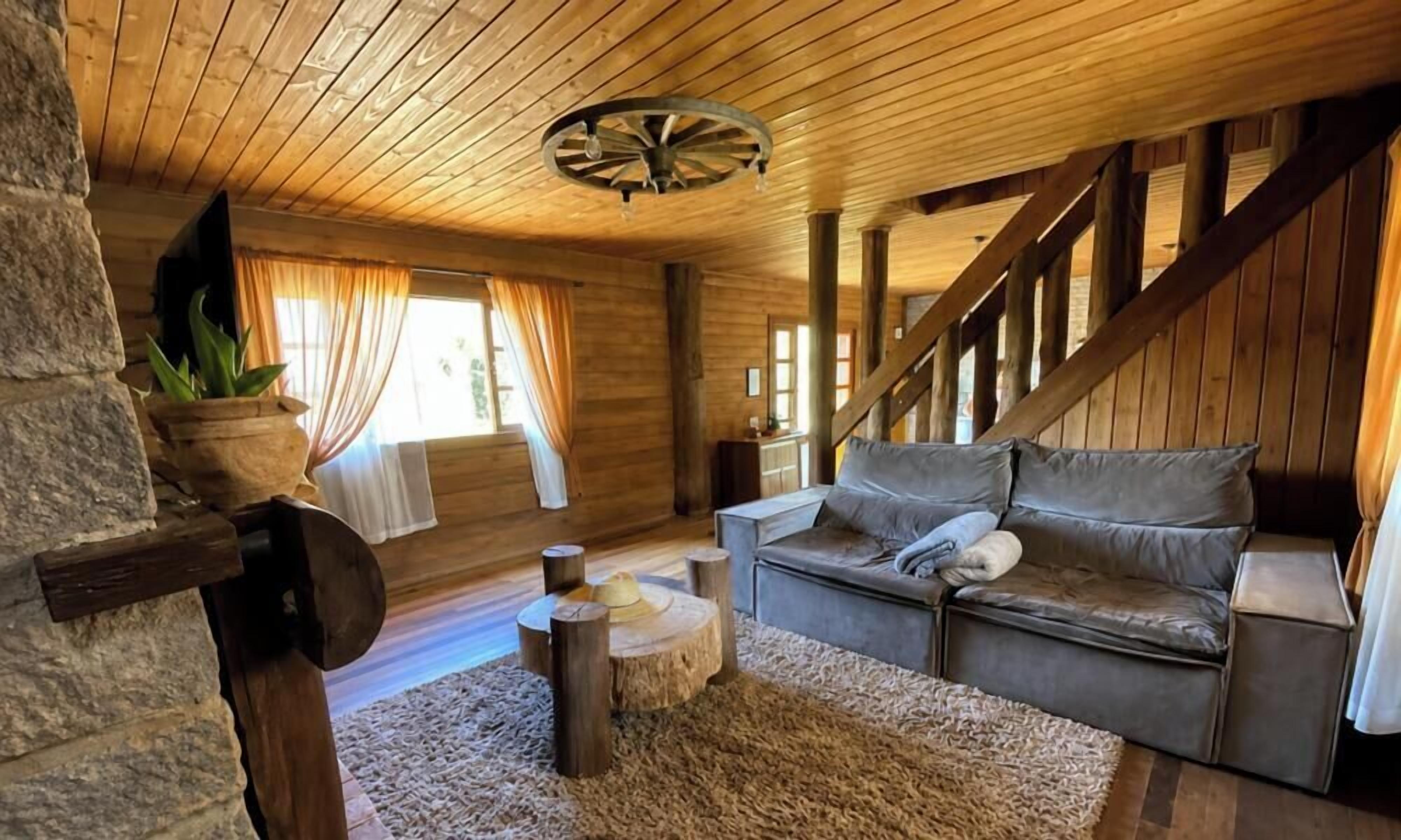 A cozy cabin interior with a wooden ceiling, a sofa, a small round table, and a potted plant.