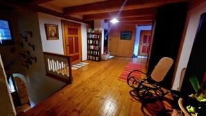 A wooden-floored interior with a bookshelf, a chair, and a door leading to another room.