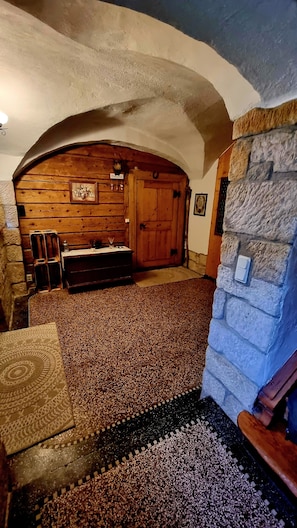A cozy room with a wooden door, a bench, and a stone wall.