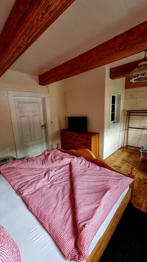A bedroom with a bed, a dresser, a television, and a window.