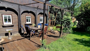 Une terrasse en bois avec des meubles d’extérieur et une pergola.