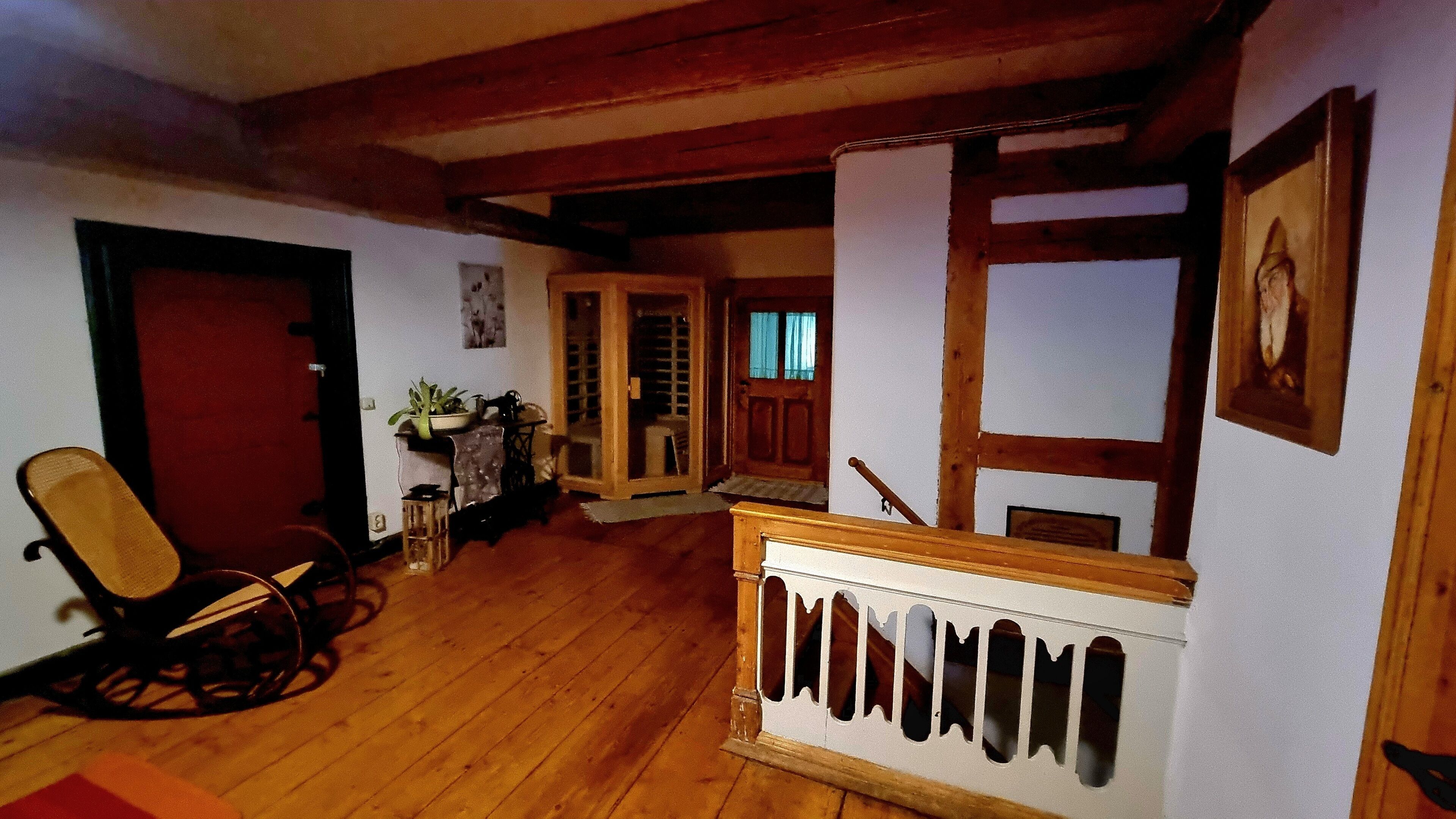 A wooden-floored interior with a chair, a small table, and a door leading to another room.