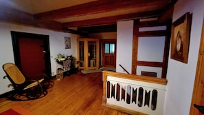 A wooden-floored interior with a chair, a small table, and a door leading to another room.