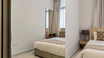 A hotel room with a bed, bedside table, lamp, and a mirror.