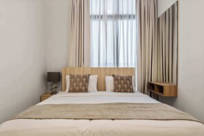Et hotelværelse med en seng, et natbord, en lampe og et spejl.