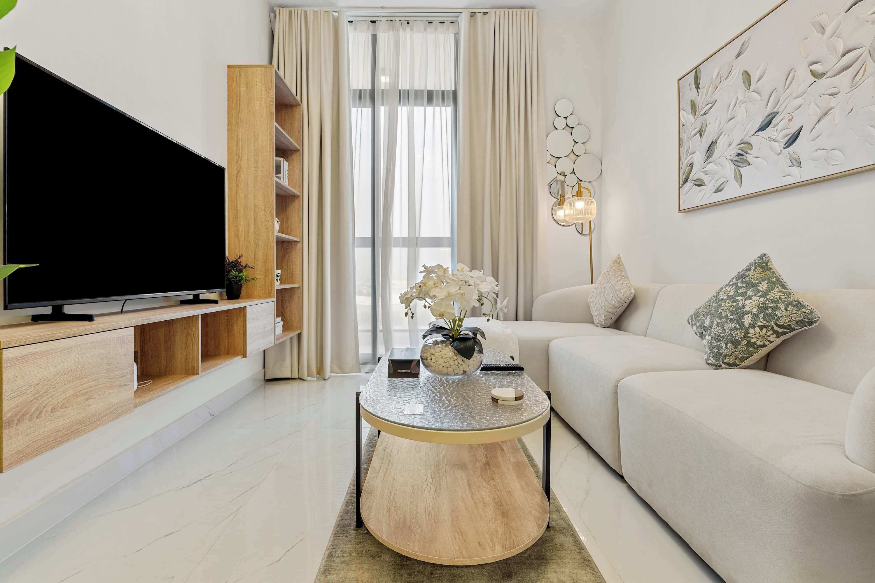 Un soggiorno moderno con una TV a schermo piatto, scaffali in legno, un tavolino rotondo, un divano e un elemento decorativo a parete.