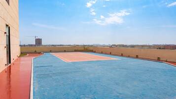 A rooftop tennis court with a clear sky and distant buildings.