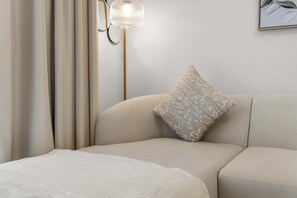 Et soveværelse med en seng, en pude, en vægmonteret lampe og et billede.