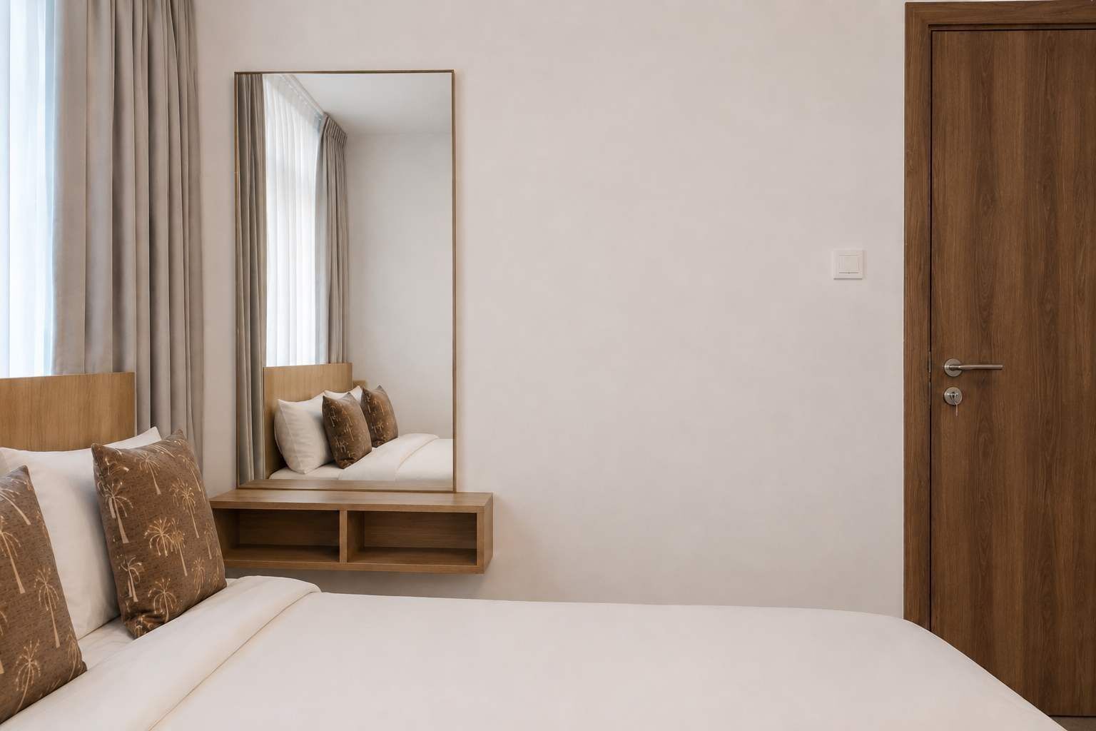 A hotel room with a bed, a wooden nightstand, a mirror, and a door.